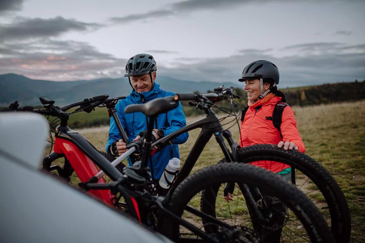 A couple happily loading their bicycles into a car in Squamish, excited for an outdoor adventure.