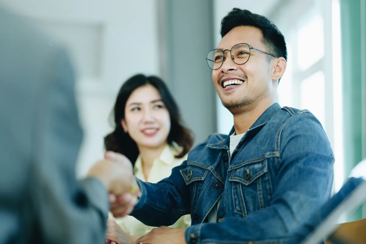 happy couple shaking hand of mortgage broker representing removing the co-signer from their mortgage
